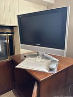 Front view of Panasonic LCD TV on stand with remote and paperwork