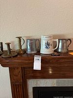 Entire lot displayed on fireplace mantel: candlesticks, tankards, stein, decorative piece