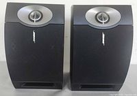 Front view of both speakers showing grilles, tweeter assemblies, and ports