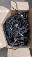 Open cardboard box filled with numerous coiled cables
