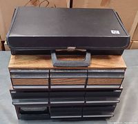 Black vinyl cassette briefcase stacked on 15-drawer plastic cabinet