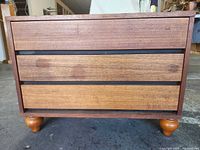 Front view showing three drawers and bun feet