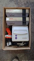 Boxed lot showing two NES consoles, one SNS-101 console, Zapper, controller, cables