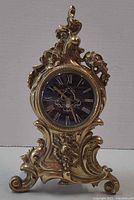 Front view of ornate brass mantel clock showing overall design