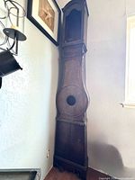 Front view of tall wooden grandfather clock case showing dial opening and empty hood