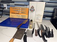 Overall view of knives, cleavers, tools and three cutlery boxes on countertop