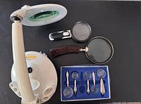 Group shot showing lamp, three handheld magnifiers and boxed set