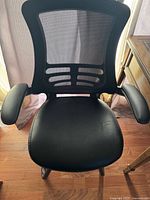 Front view of black mesh back office chair showing seat cushion and armrests