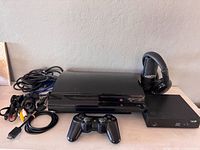 PS3 console, controller, SageTV box, headphones, cables on tabletop
