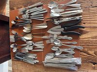 Wide view of entire assortment of flatware laid out on surface