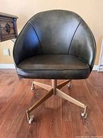 Front view of dark brown vinyl bucket chair on gold-tone four-star base with casters