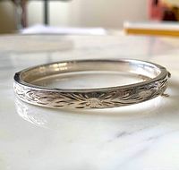 Side view of hinged sterling silver bangle showing engraved floral pattern