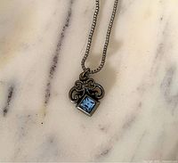 Front view of necklace showing pendant design and blue crystal