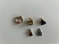 Five assorted costume jewellery charms laid out on white background