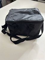 Full view of black insulated lunch bag with zipper, handles and shoulder strap