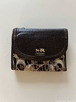 Front view closed showing leather flap, leopard fabric panel and gold Coach logo