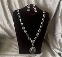 Full view of necklace on bust with pendant and earrings hung above