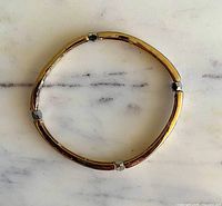 Overall view of gold-tone stretch bangle showing silver-tone spacers and circular form