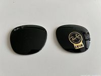 Front view of both Ray-Ban lenses; left lens shows etched logo, right lens shows original sticker