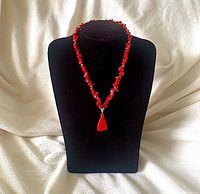 Full view of red seashell chip necklace on display bust