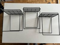 Top view of three black metal plant stands showing open cube frames and slatted tops
