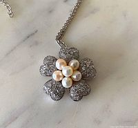 Close-up of silver-tone flower pendant showing faux pearls and pavé crystals