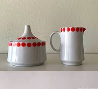 Sugar bowl with lid and creamer side by side showing pattern