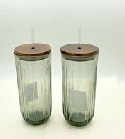 Front view of both fluted glass tumblers showing ribbed design, lids, straws
