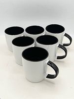 Six identical two-tone ceramic mugs displayed