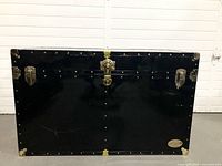 Front view of closed black Everlite trunk showing latches, lock, rivets and nameplate
