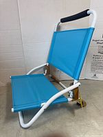 Side view of folded-out blue seat on white steel frame with foam handle