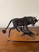 Full view of cow and calf hide statue on wood base