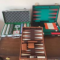 Poker chip set and green backgammon case open on dresser, brown backgammon board open in foreground