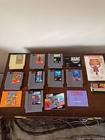 Overview of 12 NES cartridges, Game Genie cartridge, and code book on table