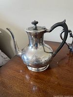 Side view of silver plate pot with etched band and black handle