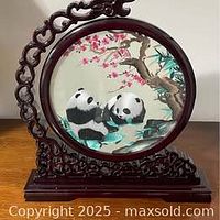 Embroidery screen on carved wood stand showing panda design