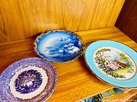 All three antique plates displayed together on wooden surface