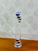 Full view of Galileo thermometer standing on wood surface