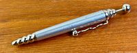 Full view of pen showing spiral tip, wavy clip and globe push button
