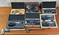 Overview of six micrometers in cases, two calipers, cables