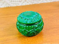 Side view of malachite glass trinket box with lid showing relief pattern