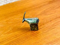 Side view of silver-plated gazelle paperweight on wood surface