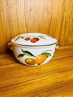 Covered casserole front view showing fruit motif and one handle