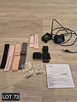 Entire lot showing two smartwatches, bands, chargers, booklet and small parts