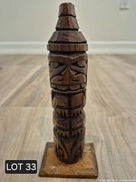 Front view of carved wooden totem figurine on base