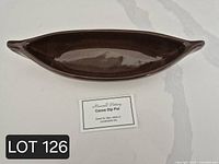Top view of brown glazed pottery canoe dip pot with Maxwell Pottery display card