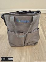 Front view of gray Norwex tote showing logo, exterior pockets, handles and shoulder strap