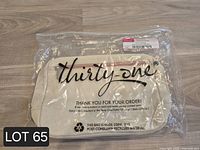 Front view of sealed Thirty-One Classic Sling Bag showing brand logo through packaging