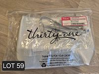 Packaged Thirty-One silver metallic tapered pouch with wrist strap visible