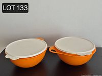 Two orange Thatsa Bowls with white lids, side view